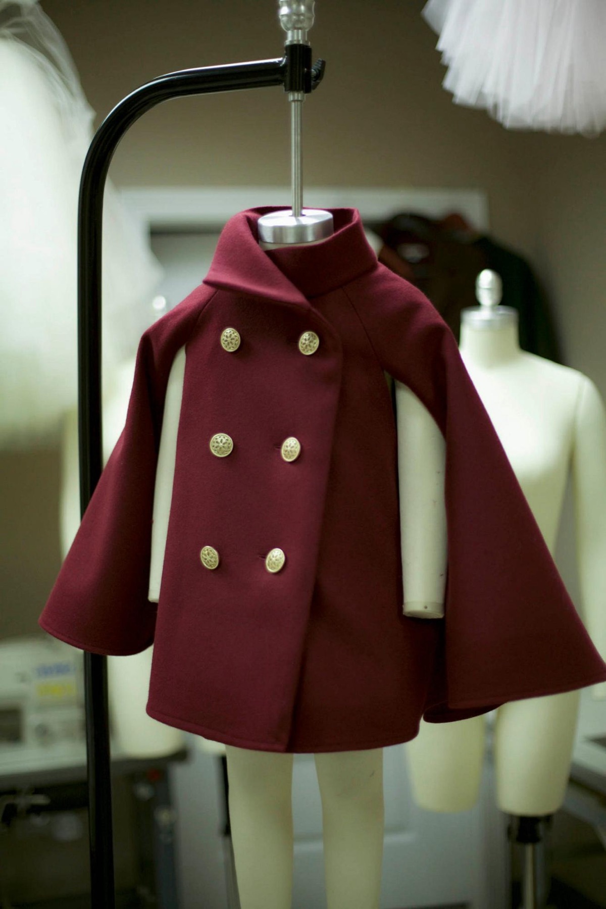 Mirabel Vance's red wine wool cape coat at Godfrey's atelier